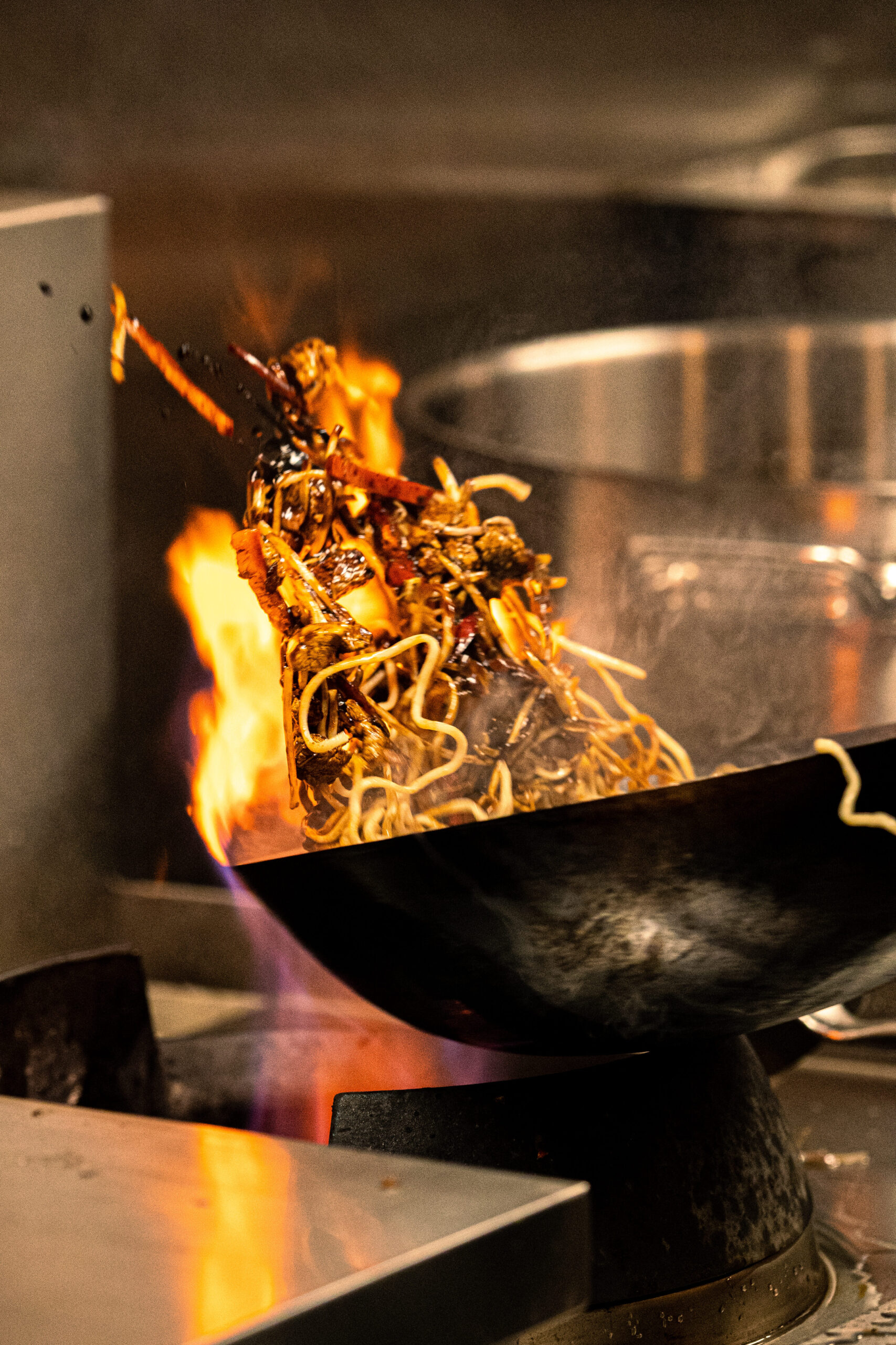 Photo de la préparation d'un plat pour FUFU Ramen. Woke qui saute des pâtes. Photo pour entreprise. Réalisation de photos et vidéos dans le domaine de la restauration pour les restaurants qui veulent améliorer leur image de marque. chaque vidéo que je réalise raconte votre histoire en mettant en lumière vos valeurs et vos objectifs